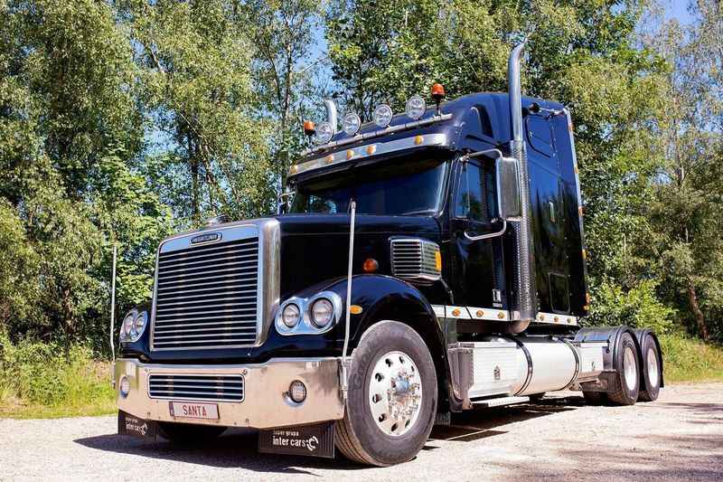 Zwarte roadshowtruck met oplegger onderweg