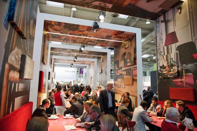 Druk restaurant met rode banken onder witte portalen