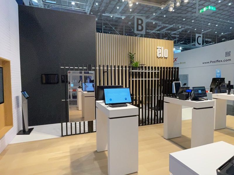 Touchscreens op witte tafels onder een houten latwerk