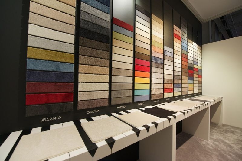 Wand met tapijtstalen in alle kleuren boven een witte stalentafel