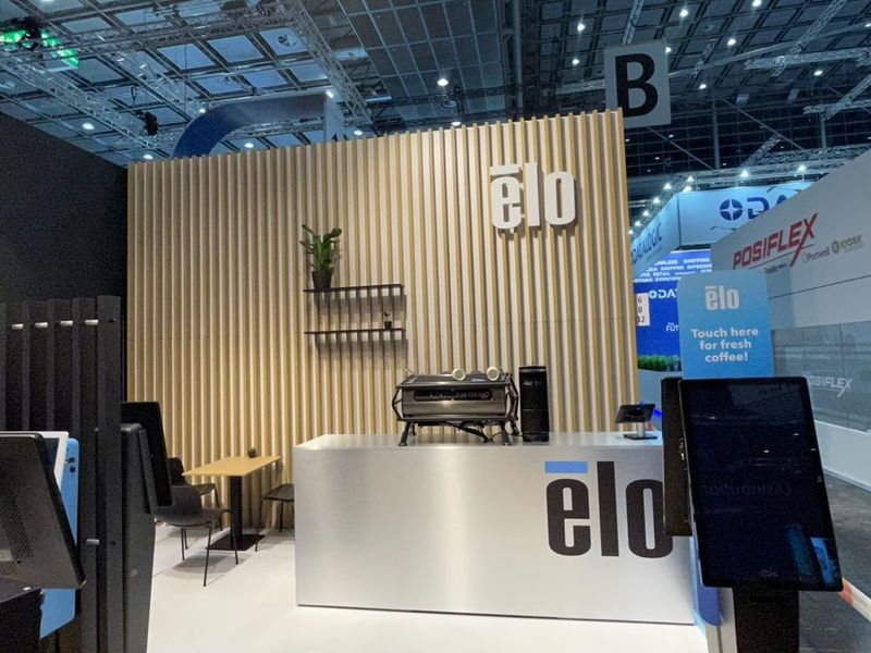 Witte balie met het logo van ELO voor een wand met houten latten